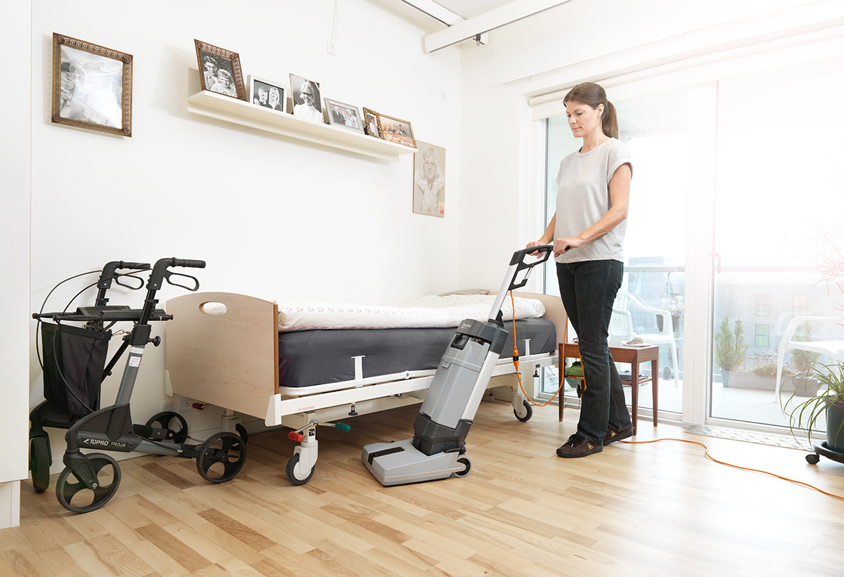 Μια γυναίκα καθαρίζει το χώρο ενός δωματίου.